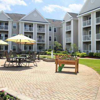 A well-maintained apartment complex courtyard featuring outdoor seating and umbrellas.