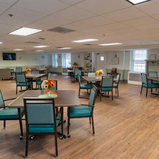 A spacious and well-lit dining area with tables and chairs arranged for communal activities.