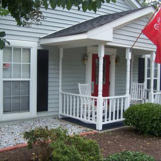 A cozy house with a front porch, red door, and a flag displayed outside.