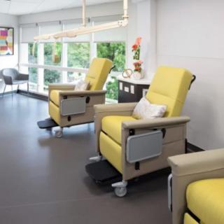 A modern clinic waiting area with comfortable yellow recliner chairs and large windows.