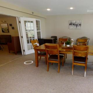 A cozy dining room with a wooden table and chairs, featuring artwork on the walls.