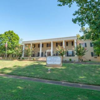 A historic building with large columns and a well-maintained lawn on a sunny day.