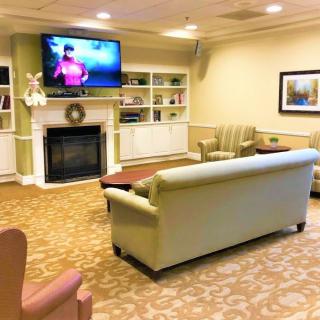A cozy living room with a sofa, coffee table, and a television mounted above a fireplace.