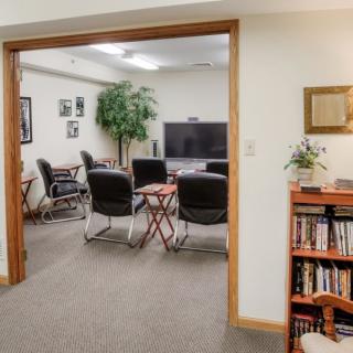 A small office conference room with a television, chairs, and a bookshelf.