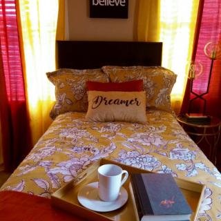Cozy bedroom setup with a book and cup of coffee on a tray.