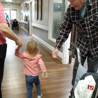 A joyful moment as a child walks hand-in-hand with an adult in a hallway.