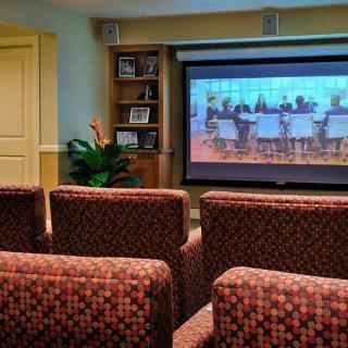 A cozy home theater room with patterned seating and a large screen displaying a movie.
