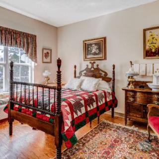 A cozy vintage bedroom with an antique wooden bed and a colorful quilt.