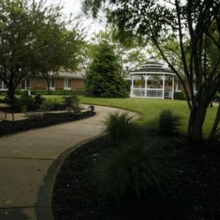 A serene garden pathway leading to a gazebo surrounded by lush greenery.
