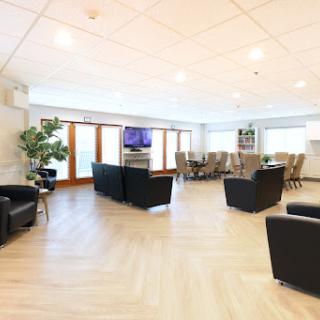 A modern lounge area featuring comfortable seating, a television, and large windows that provide ample natural light.