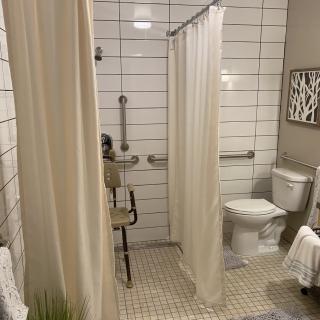 A modern bathroom with accessible features, including a tiled shower area and safety bars.