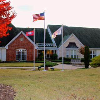 A charming residential building surrounded by well-maintained landscaping and flying flags.