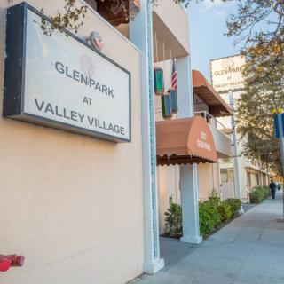A view of the Glenpark at Valley Village apartment building with signage and sidewalk in the foreground.