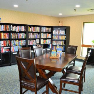 A cozy library reading area with a wooden table and chairs surrounded by bookshelves.