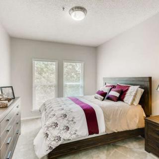 A cozy bedroom with a neatly made bed, featuring elegant bedding and natural light streaming through the windows.