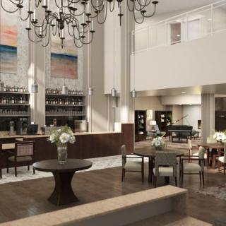 A spacious hotel lobby with elegant chandeliers, modern furniture, and floral arrangements.