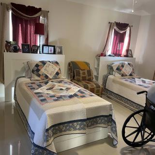 A cozy bedroom with two single beds, a wheelchair, and framed photos on display.