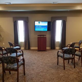 A small meeting room with chairs arranged facing a television screen.