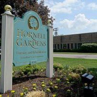 Entrance sign for Brownell Gardens with a building in the background.