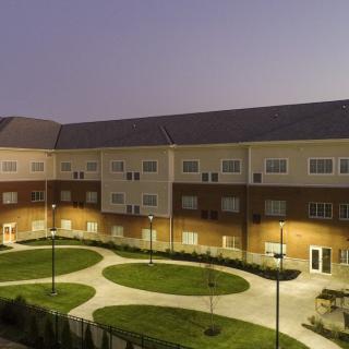 A well-lit residential building with a landscaped courtyard at night.