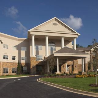 A large residential building with prominent columns and a circular driveway.