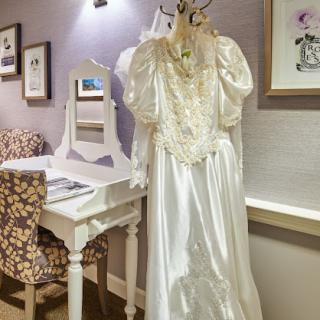 A beautiful bridal gown displayed in an elegant bedroom setting.