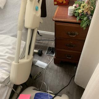 A snapshot of a bedroom corner featuring a nightstand, medical equipment, and visible cables.