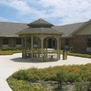 A landscaped courtyard featuring a wooden gazebo surrounded by pathways and greenery.