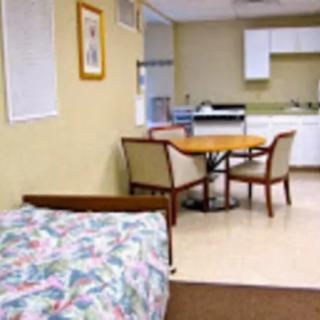 A small room with a bed, kitchenette, and dining area.