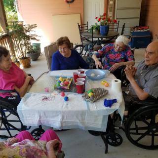 A group of elderly individuals sitting around a table outdoors, enjoying each other's company.