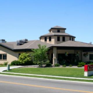 A healthcare clinic building with a landscaped lawn and a road in front.