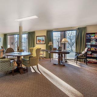 A cozy living room with comfortable seating, large windows, and a bookshelf.