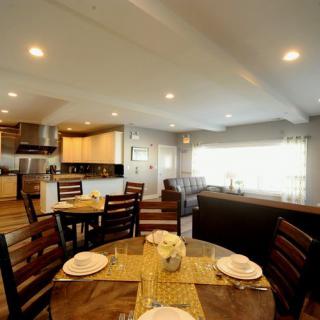 A cozy dining area with a wooden table set for a meal, adjacent to a modern kitchen.