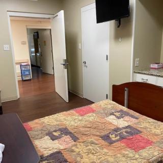 A view of a hospital room with a bed, television, and open doors leading to a hallway.
