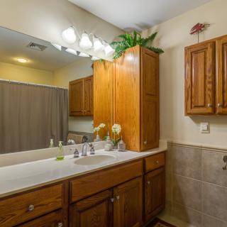 A bathroom with a large mirror, wooden cabinets, and modern fixtures.