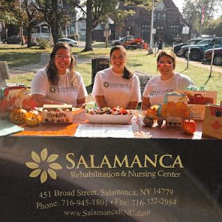 Three women representing Salamanca at a community event, promoting their services with a decorated table.