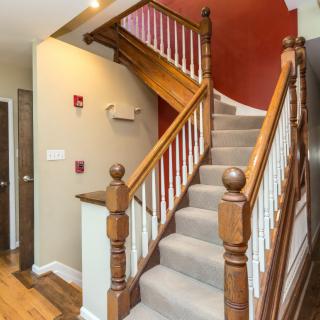 A wooden staircase with carpeted steps and decorative banisters in a home interior.