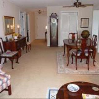 A traditional living and dining area featuring a wooden dining set, grandfather clock, and classic decor elements.