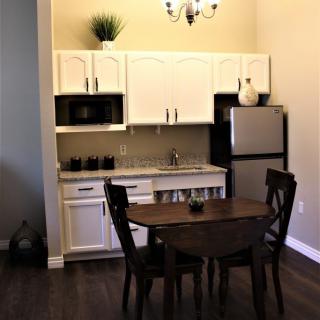 A cozy kitchen and dining area with white cabinets, a round table, and modern appliances.