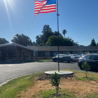 An American flag waving proudly on a flagpole in front of a building during a sunny day.