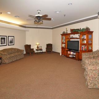 A spacious living room with sofas, a television, and a ceiling fan.
