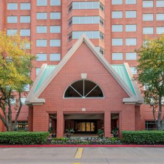 Front entrance of a brick hotel with trees on either side.