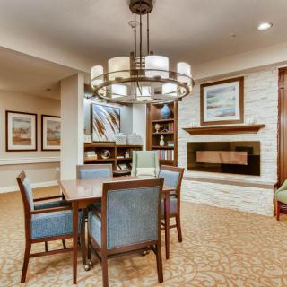 A modern living and dining area featuring a central chandelier, fireplace, and stylish artwork.