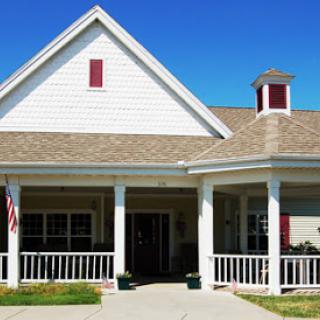 A charming residential house with a welcoming front porch under a clear blue sky.