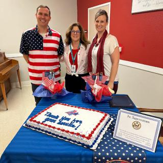 A festive gathering featuring a patriotic cake and attendees dressed in American-themed attire.
