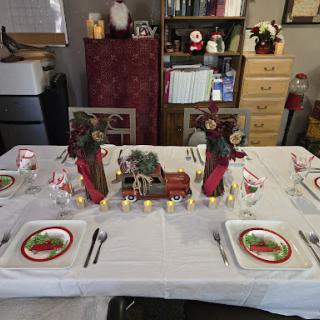 A beautifully decorated dining table for a Christmas celebration, featuring festive colors and a charming train centerpiece.
