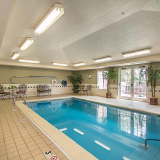 An indoor swimming pool area with lounge chairs and natural lighting.