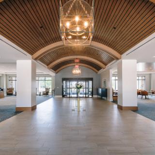 A spacious and elegantly designed lobby featuring a wooden arched ceiling and modern lighting.