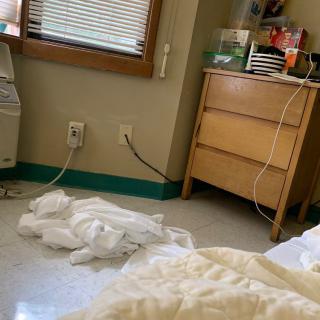 A hospital room with a dresser, cables, and a blanket on the floor.