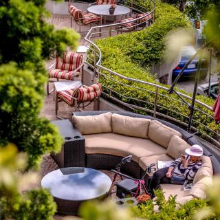 A cozy outdoor terrace with comfortable seating surrounded by lush greenery.